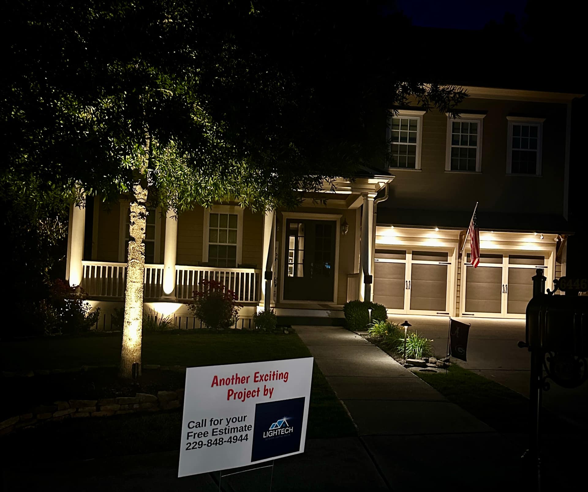 Professional outdoor lighting project yard sign in front of a warmly lit North Georgia home